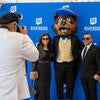 Mascot poses with 2 people and photographer